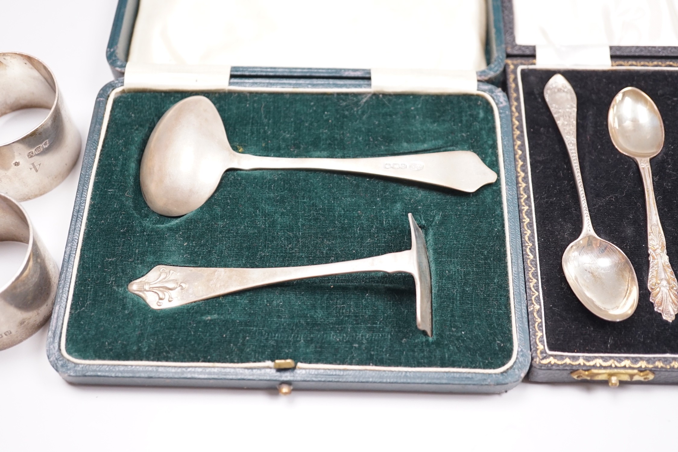 A pair of George V silver napkin rings, Edward Barnard & Sons Ltd, London, 1916 and two cased sets of silver cutlery, coffee spoons and spoon and pusher.